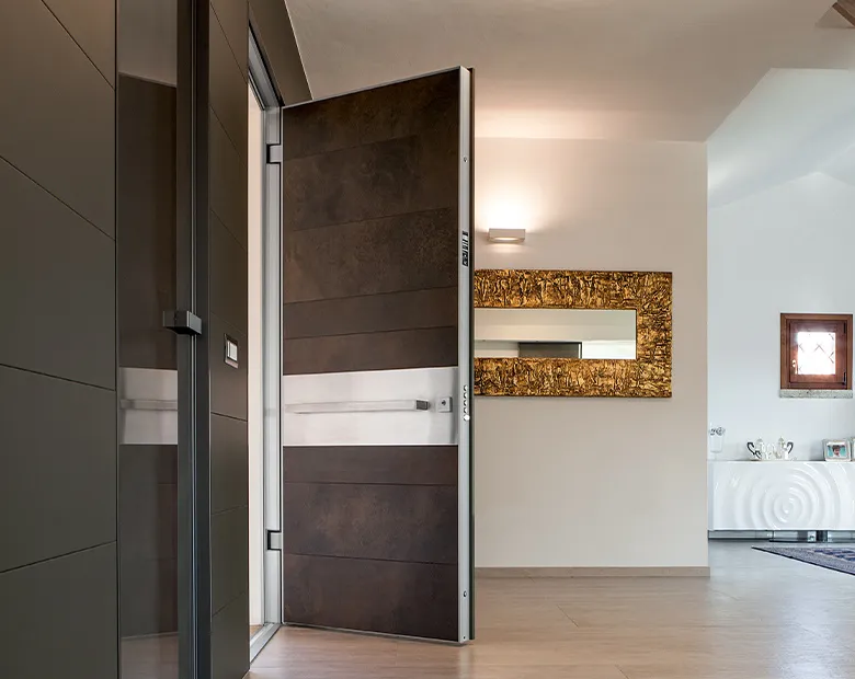 Rusted-bronze aluminium door with a brushed-steel horizontal band shown ajar from a bright living space