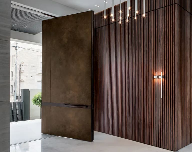 Charcoal horizontal-lined pivot door open in daylight with a warm timber-clad reveal and garden view
