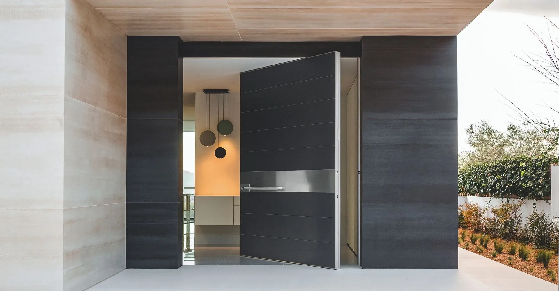 Charcoal pivot front door standing open at a daylight entrance