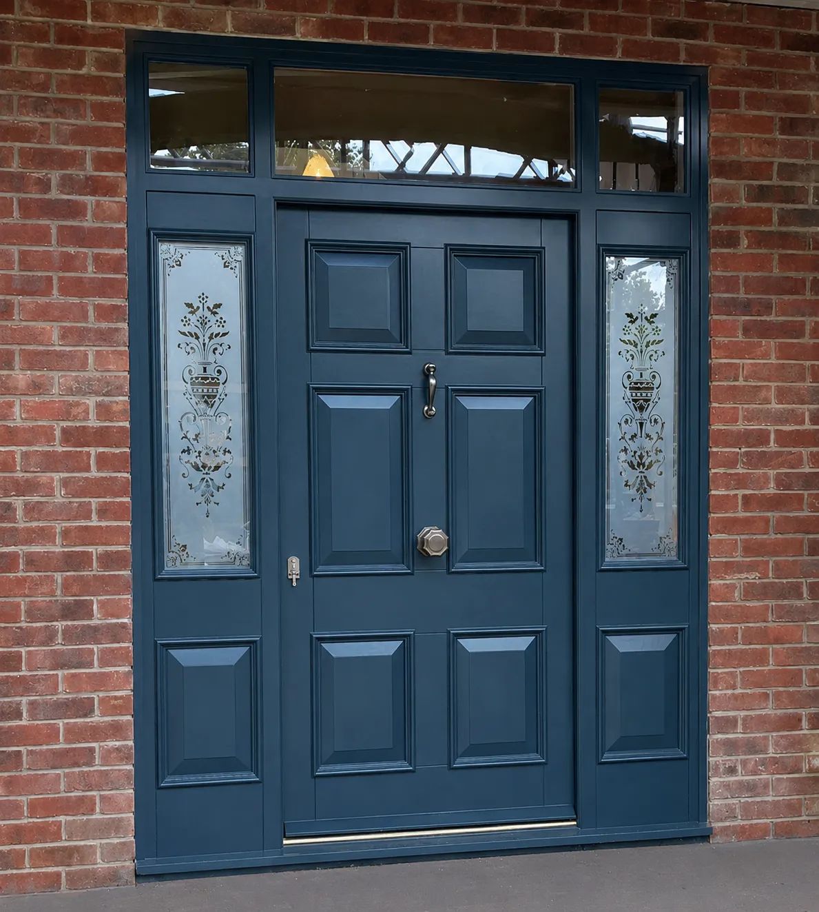 Petrol-blue panelled steel door with etched-glass sidelights and transom and brass furniture on a red-brick house