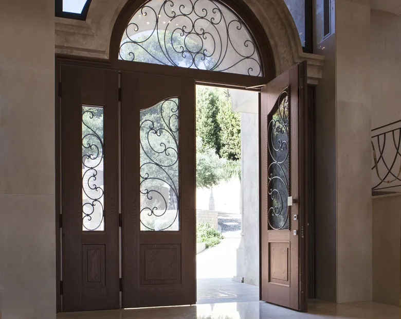 Dark walnut steel double doors with wrought-iron glazed panels beneath an arched ironwork fanlight
