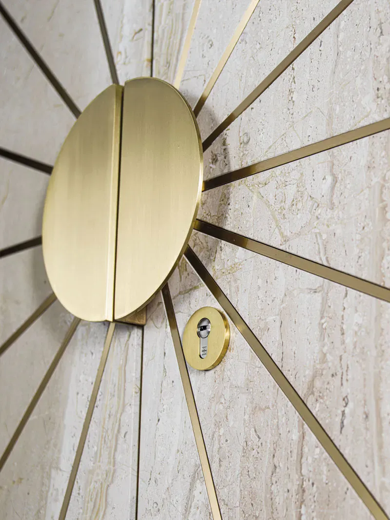 A marble-effect door with a brushed-brass sunburst inlay, half-moon handle and a chrome lock cylinder