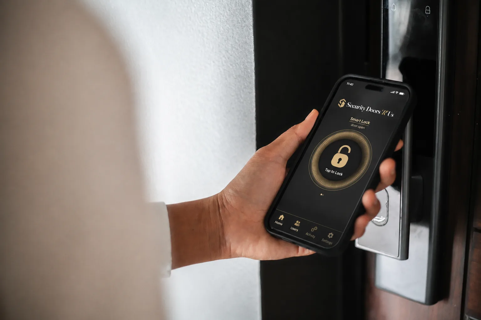 A phone held at a dark front door, the smart-lock app on screen ready to unlock